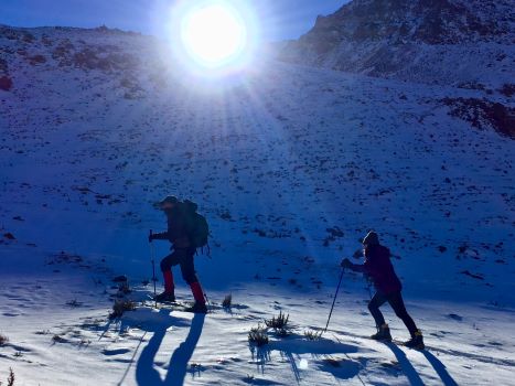 Dos personas suben una pendiente de nieve con raquetas en Vallecitos-Mendoza.