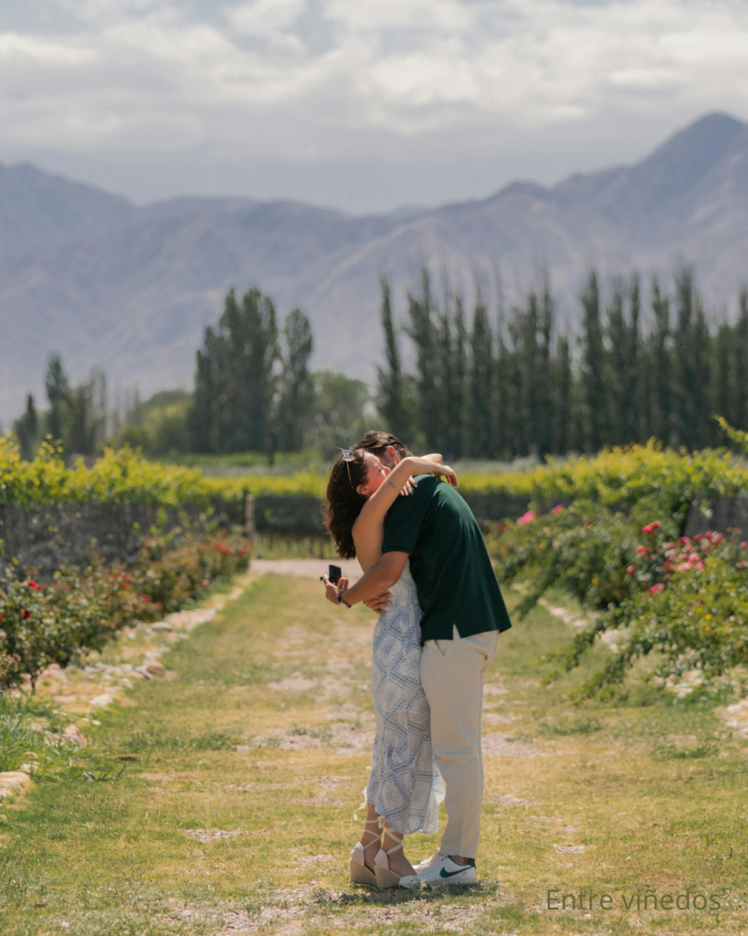 Viñedos al pie de la cordillera de los andes con pareja dándose un abrazo.
